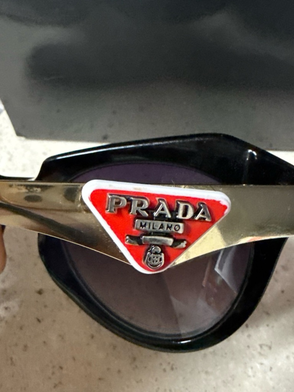 Prada Women's Sunglasses Black Frame with Red Triangle Logo and Gold Accents